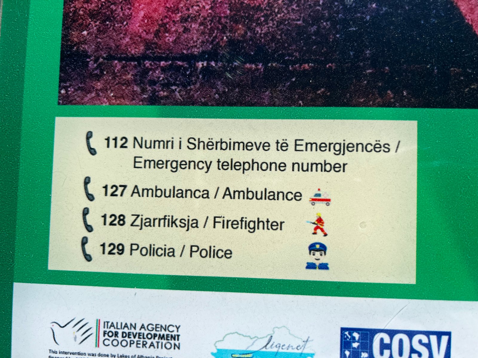 Albanian emergency telephone numbers sign: 112 general emergency, 127 ambulance, 128 fire, 129 police