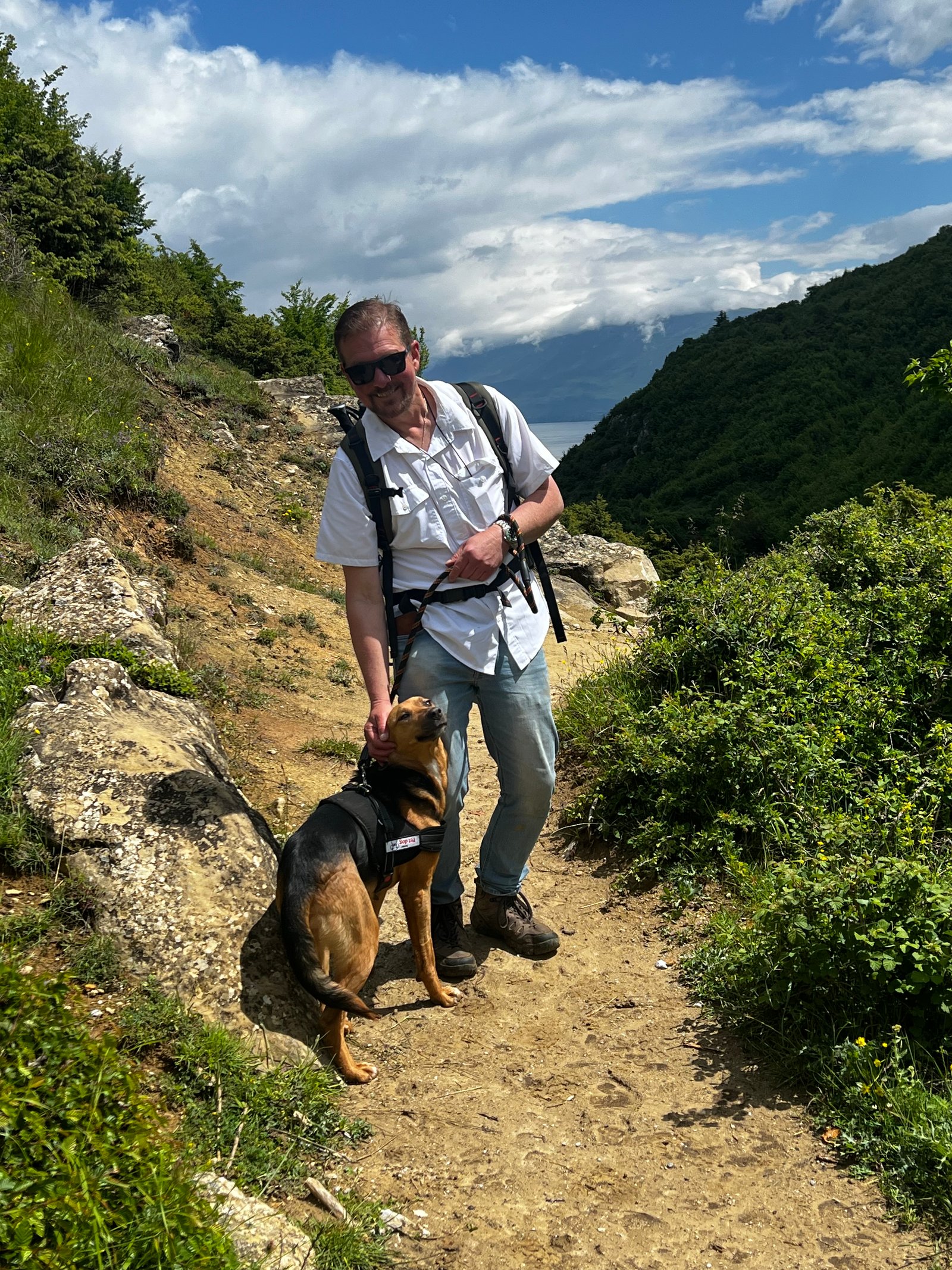 Hiker and dog on a dramatic cliff-edge trail in the Albanian mountains